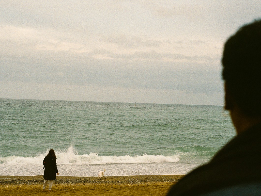 Au loin, une femme et son chien sur la Barceloneta face à la mer