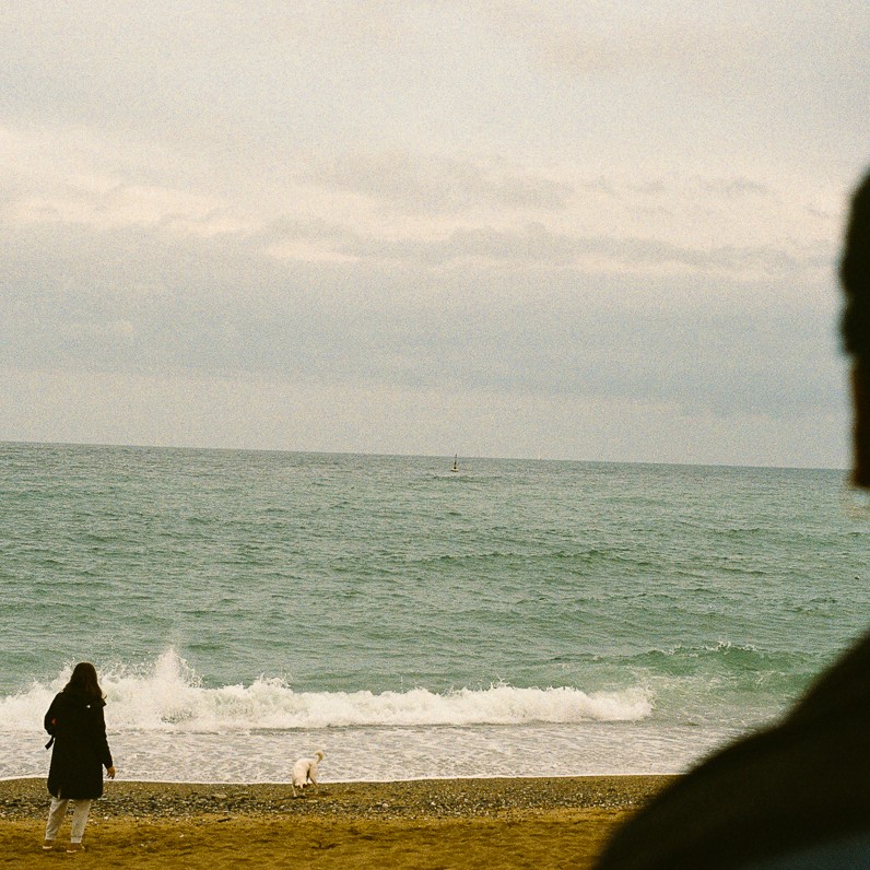 Au loin, une femme et son chien sur la Barceloneta face à la mer